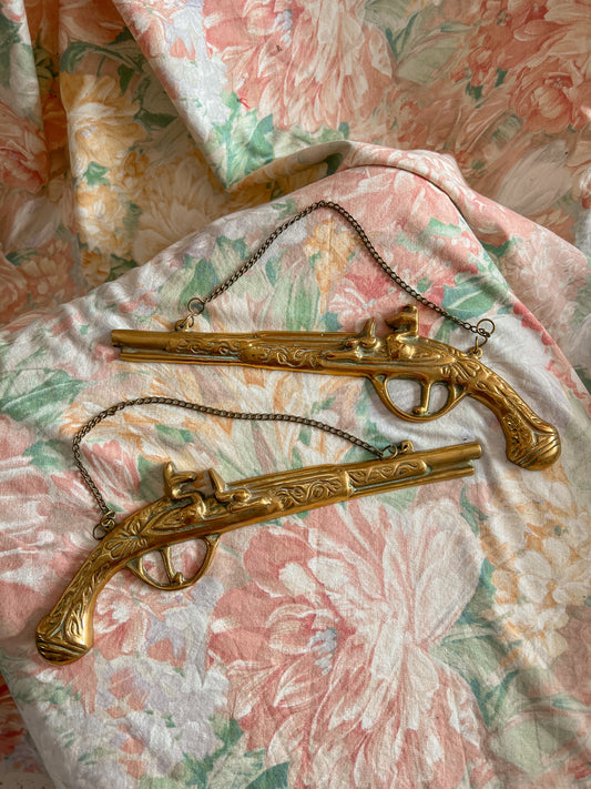 A pair of vintage brass hanging pistols.